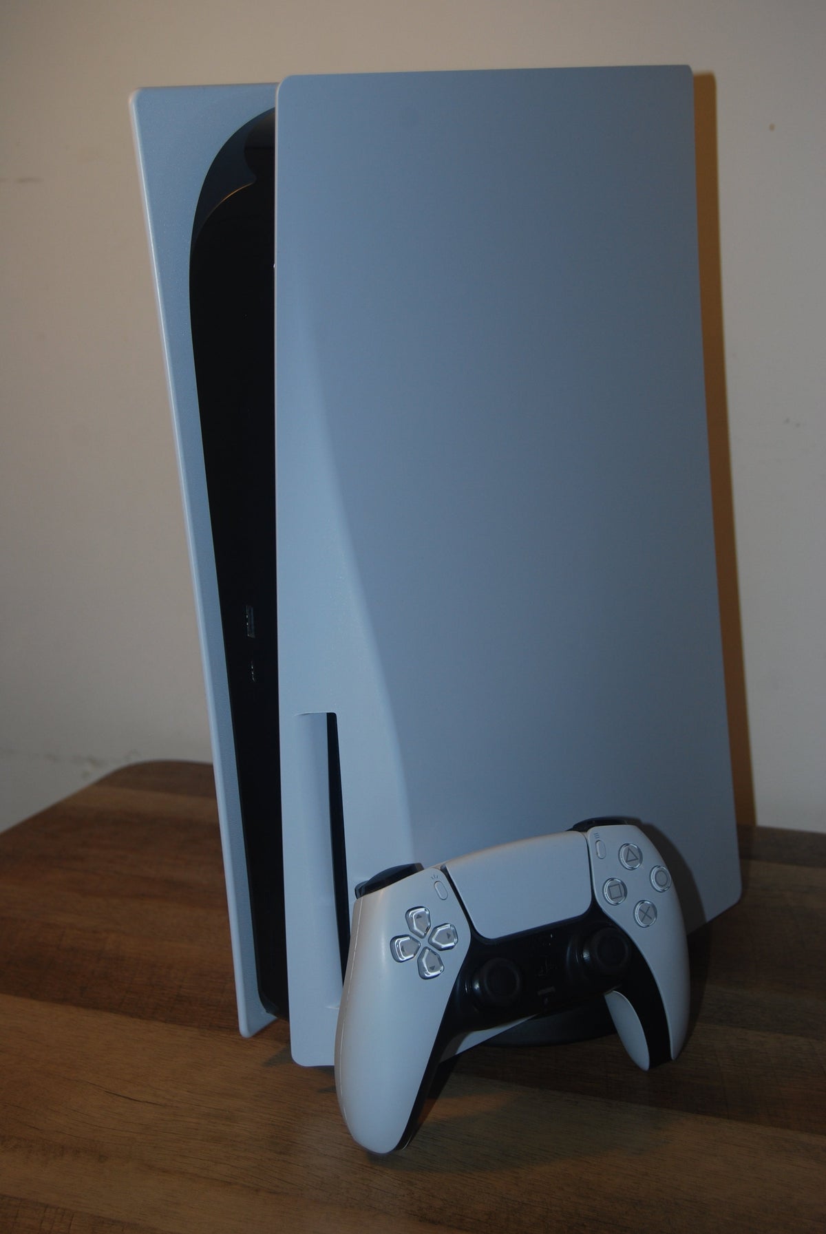 Standard PlayStation 5 console standing beside a white DualSense controller