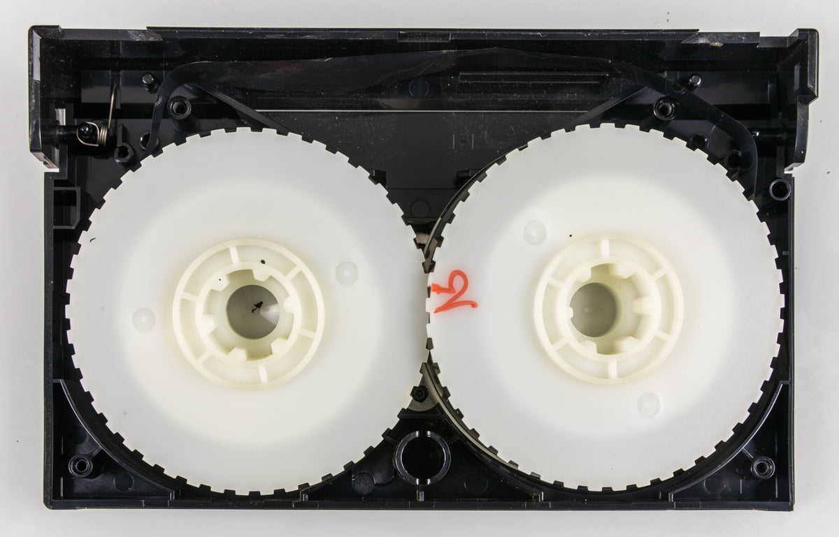 An illustrative opened Betamax videocassette showing magnetic tape and reels, not an EA source tape