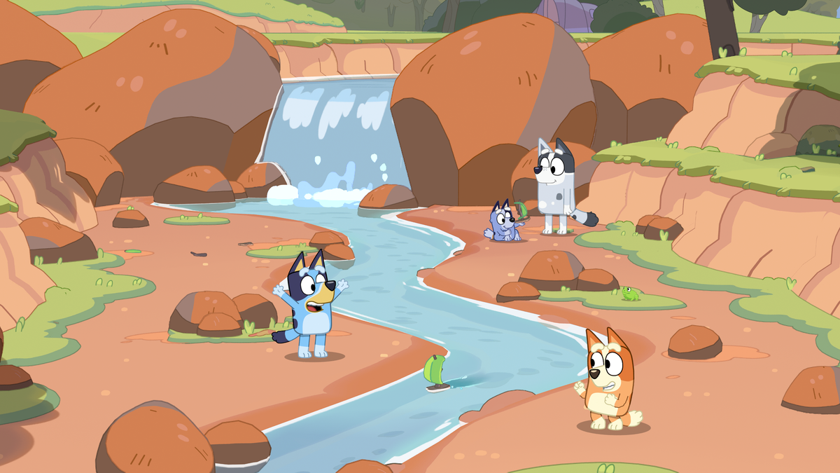 Bluey and Bingo playing in a creek area with Bandit in Bluey’s Happy Snaps