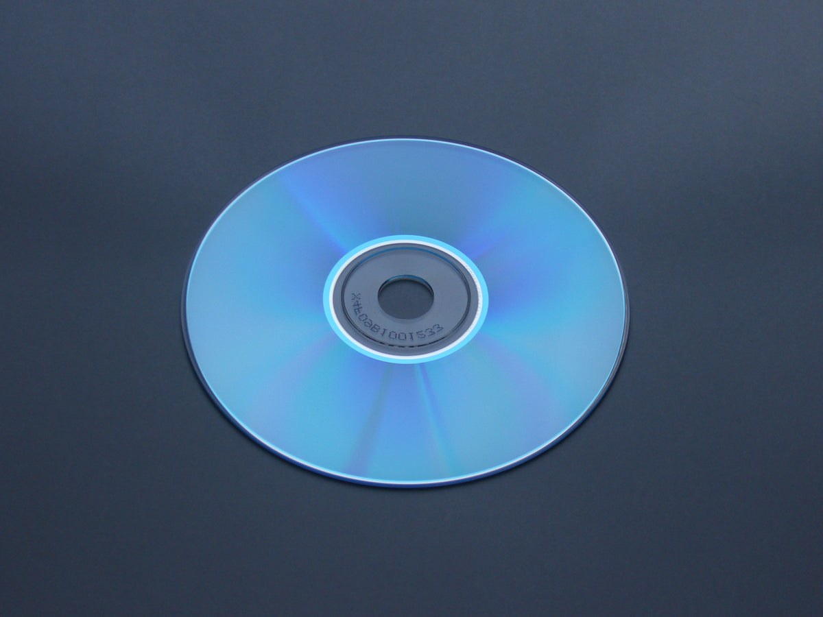 Underside of an optical disc against a gray background, used as an example of the surface that should be cleaned carefully