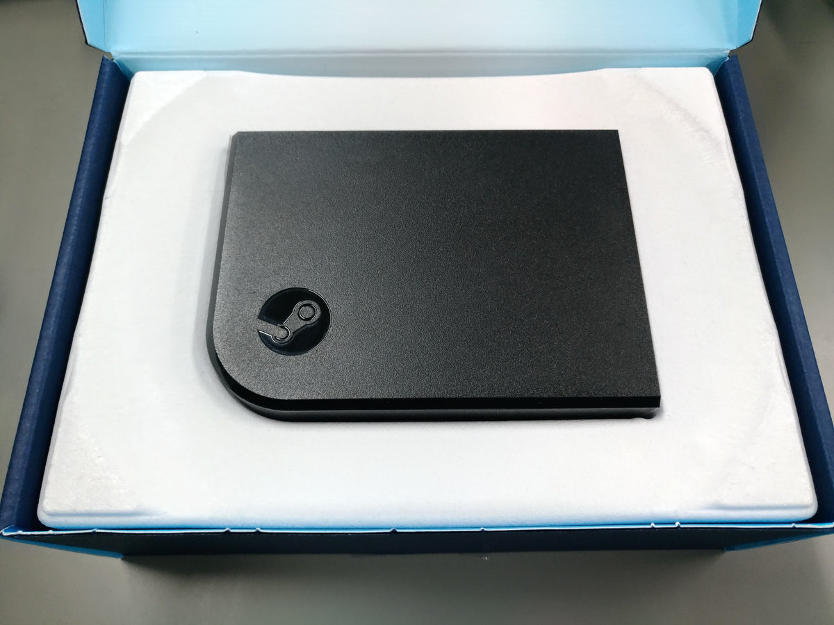 Physical Steam Link receiver resting in the white insert of its open blue package