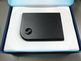 Physical Steam Link receiver resting in the white insert of its open blue package