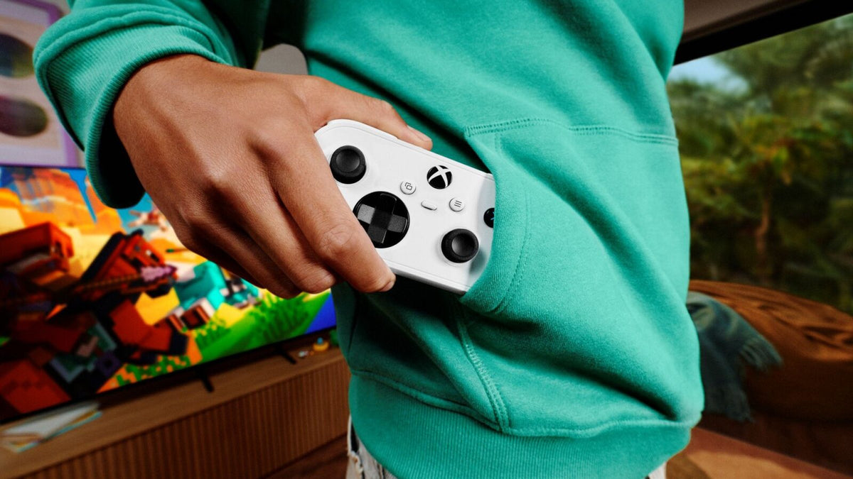 Official Xbox Nano Controller image showing a person holding the compact white controller beside a hoodie pocket