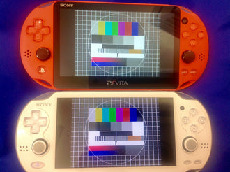 White PCH-2000 and black PCH-1000 PlayStation Vita handhelds shown together