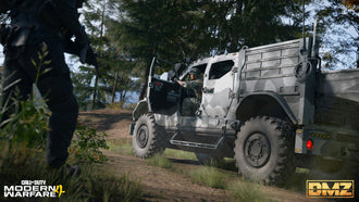 An operator entering an armored military vehicle alongside another armed teammate in a wooded setting.
