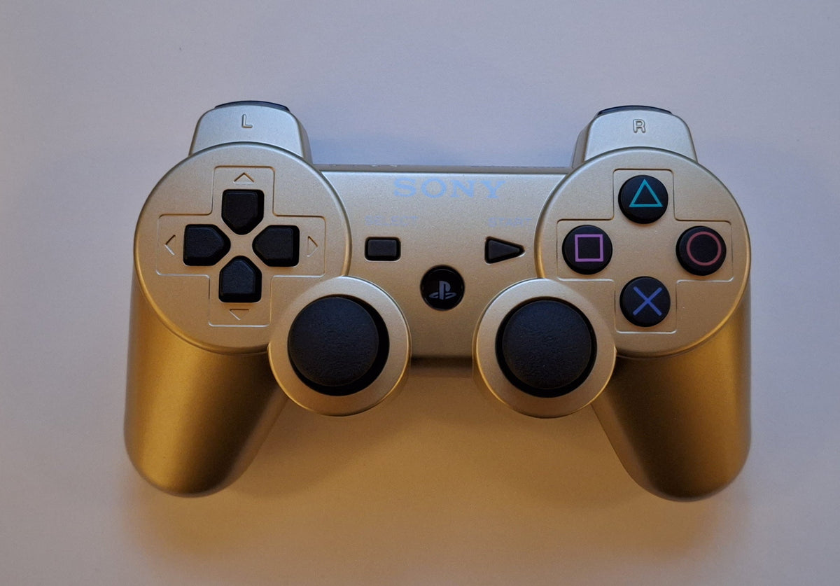 Gold-colored PlayStation 3 DualShock 3 controller with its front buttons and analog sticks visible
