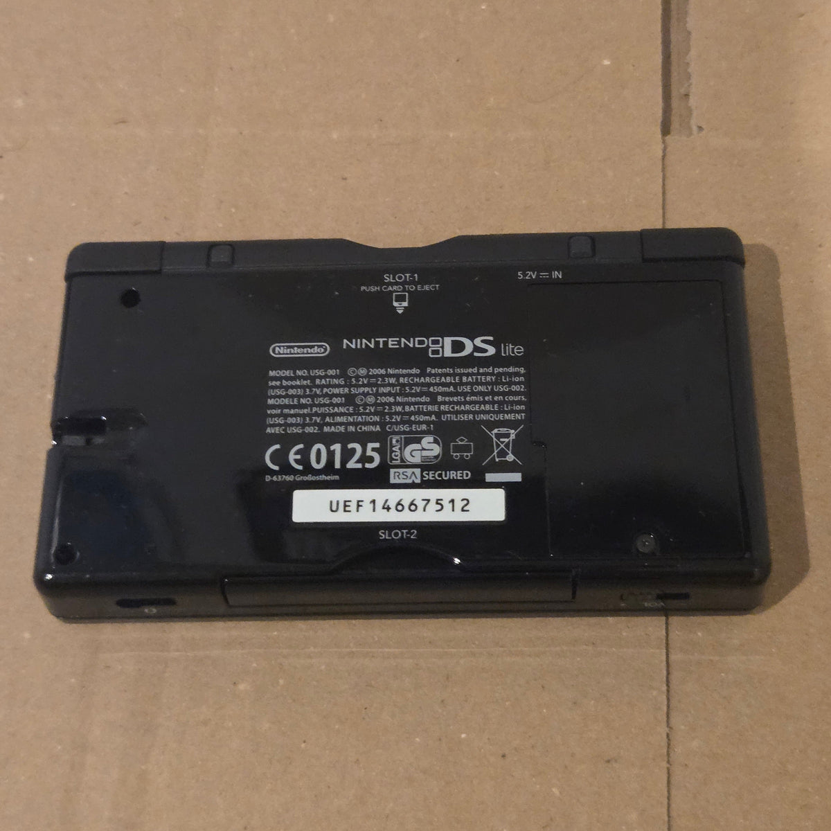 Underside of a closed black European Nintendo DS Lite with SLOT-1 and SLOT-2 labels visible