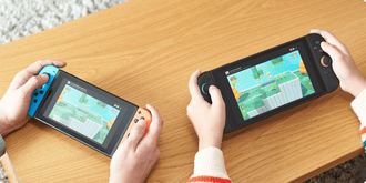 Two people holding Nintendo Switch consoles side by side demonstrating local multiplayer gameplay via GameShare.